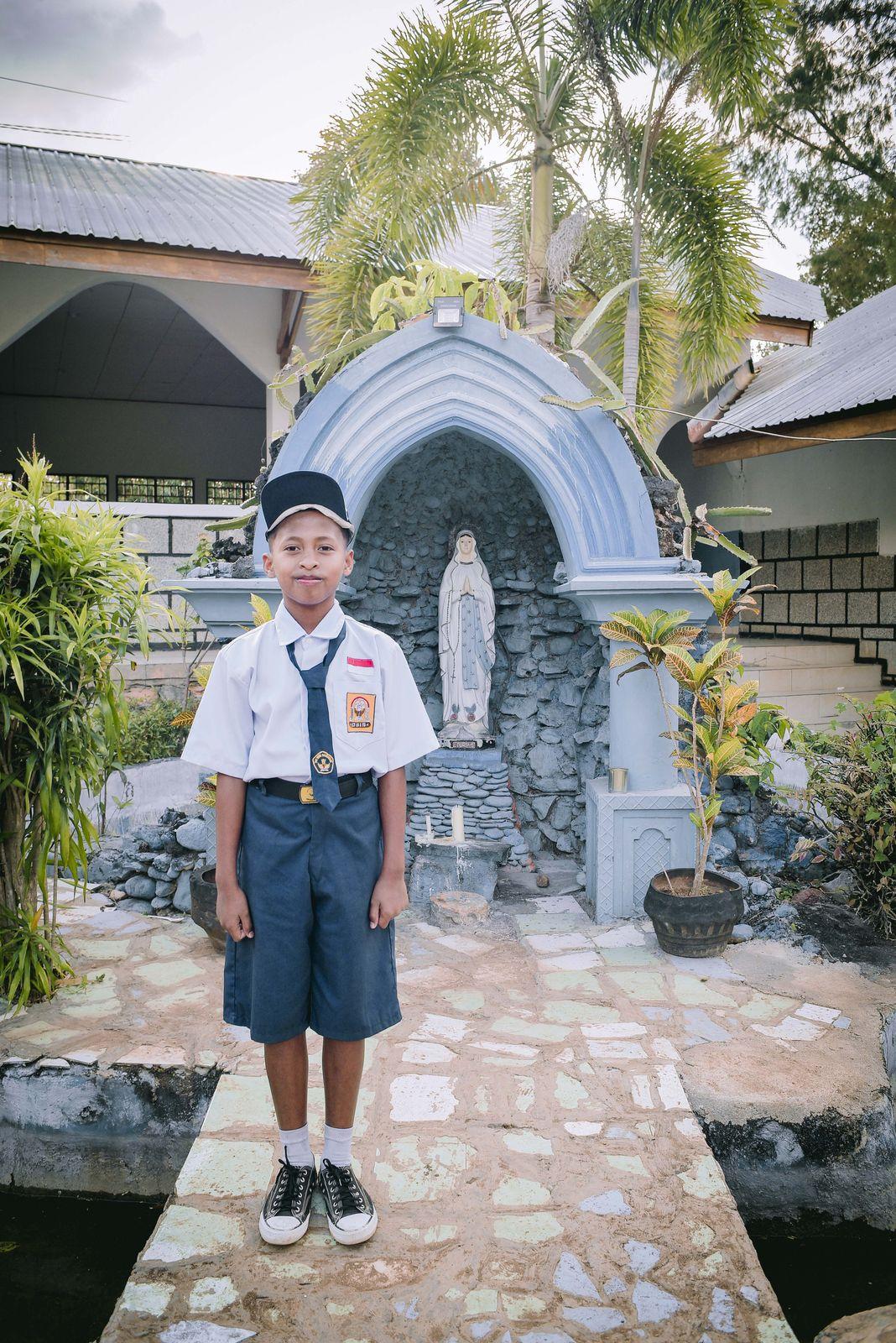 Seorang anak berseragam pramuka di depan gua Maria